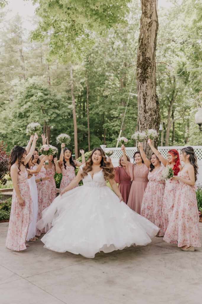 A bride twirling in a ball gown surrounded by her bridesmaids holding up their bouquets.
